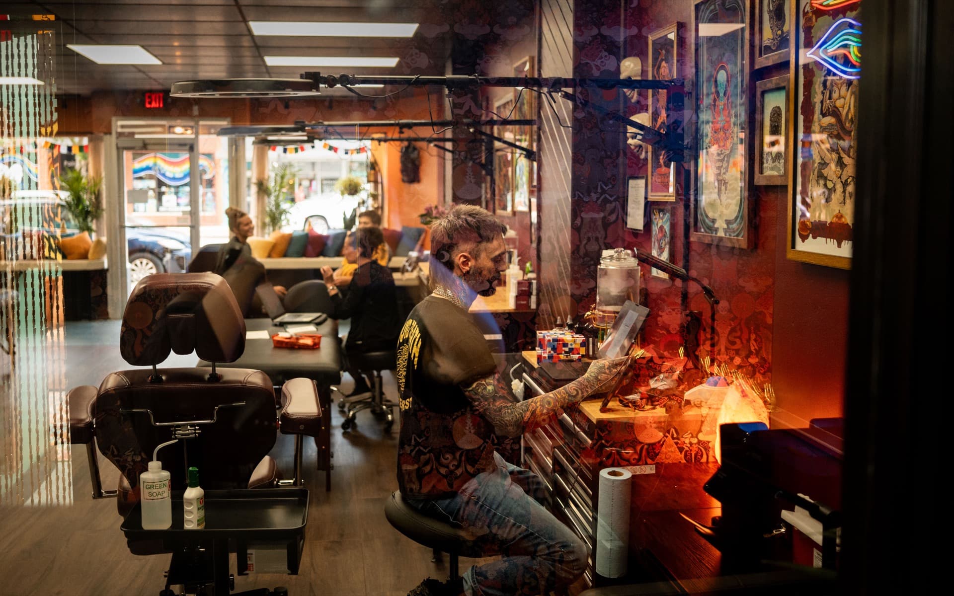 Mystic Tattoo Collective studio interior with a tattoo artist at work among burgundy walls and framed artwork